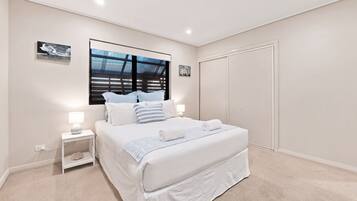 A bedroom with a large bed, bedside tables, a wardrobe, and artwork on the walls.