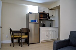 A compact kitchen with a refrigerator, microwave, and white cabinets. - One Bedroom Apartment on Niagara Gorge w free breakfast! (Niagara Falls)