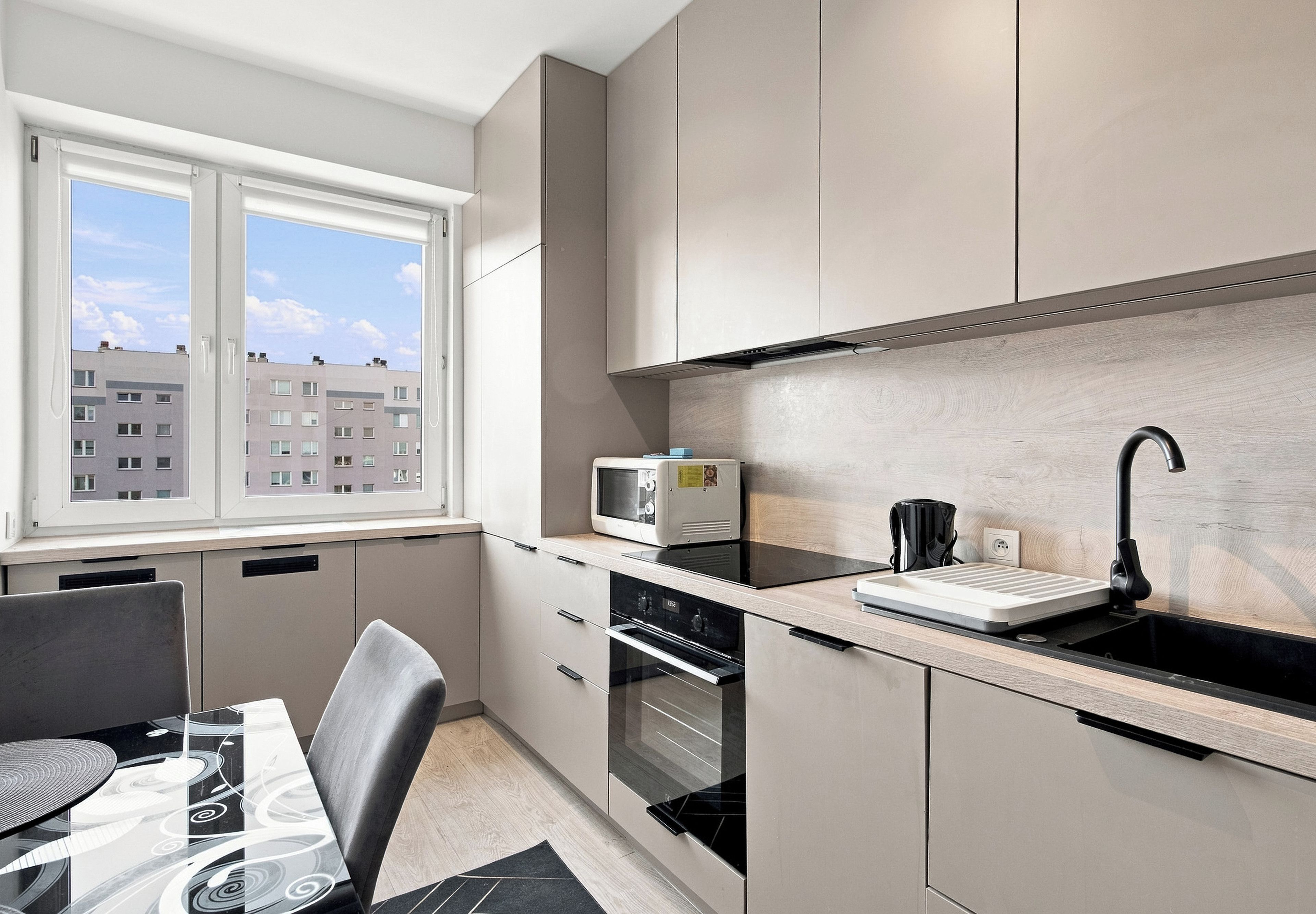 Una cucina moderna con finestra, elettrodomestici integrati e zona pranzo.