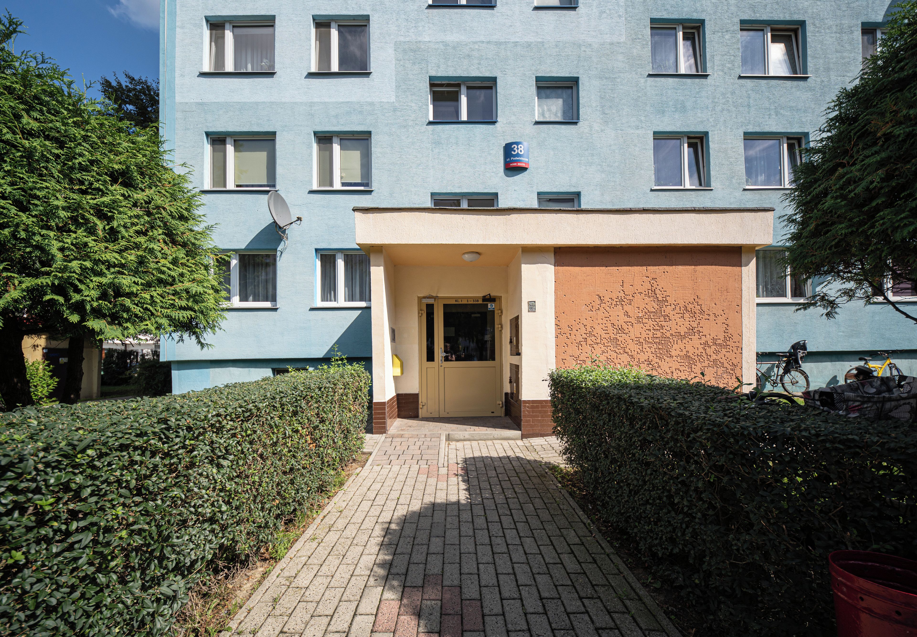 Un immeuble à la façade bleue, avec une entrée au rez-de-chaussée et une enseigne indiquant le numéro 38.