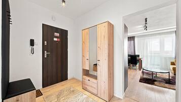 A modern hotel room with a wooden wardrobe, a desk, and a dining area.