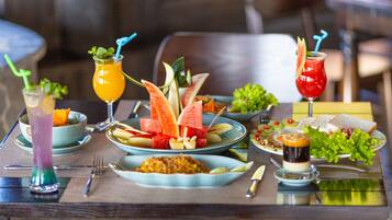 Una mesa de comedor con varios platos, bebidas y una ensalada.