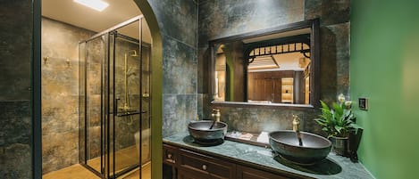 A modern bathroom with a glass-enclosed shower, two vessel sinks, and a large mirror.