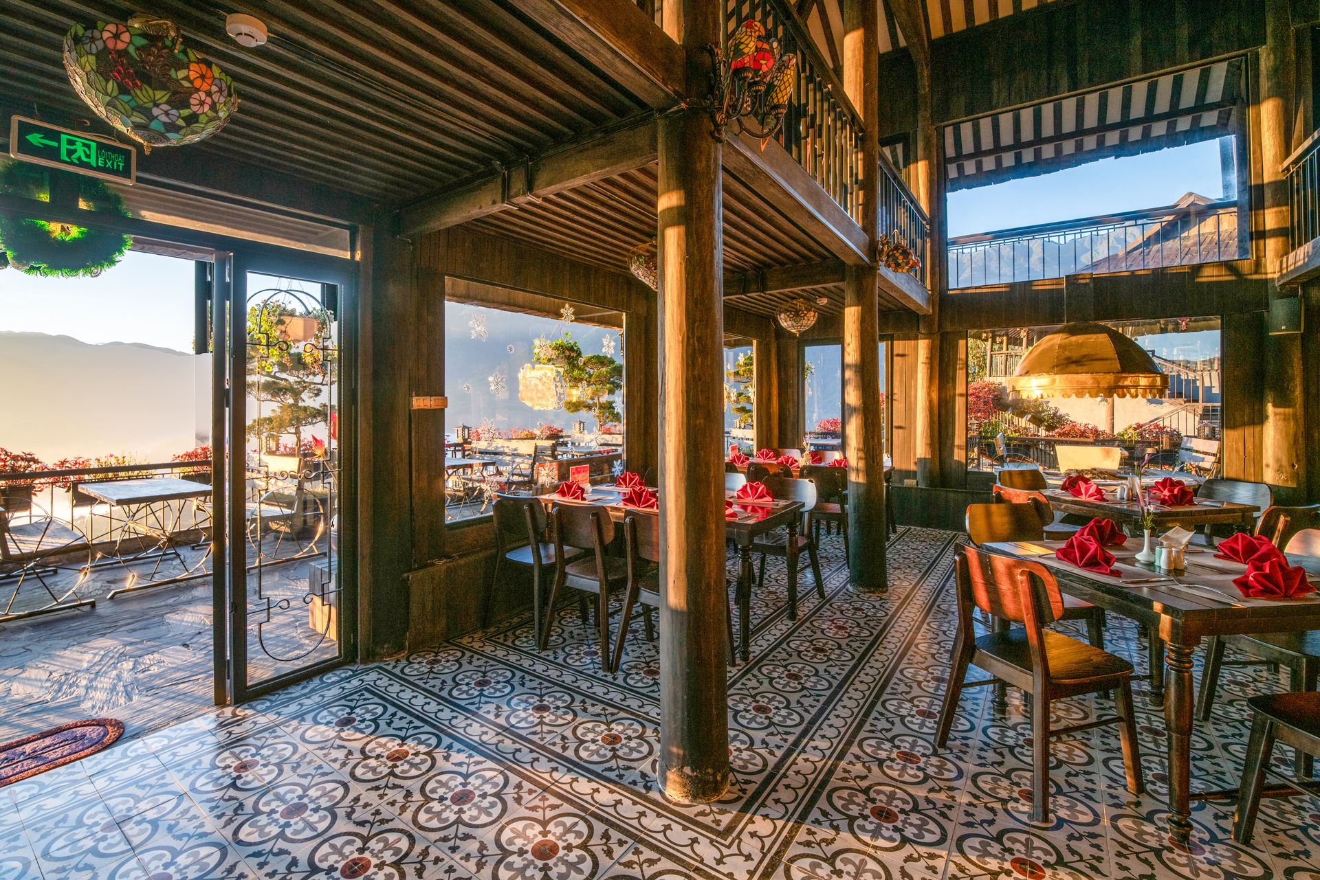 An indoor dining area with tables and chairs, a view of the outdoors, and a ceiling with exposed beams.