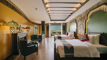 Habitación de hotel con una cama grande, un sofá, un escritorio y vistas a la montaña.