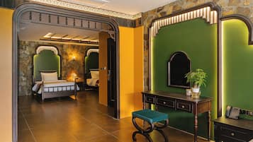 Une chambre d’hôtel avec un lit, un bureau avec un téléphone, une chaise et un mur vert agrémenté d’un miroir.