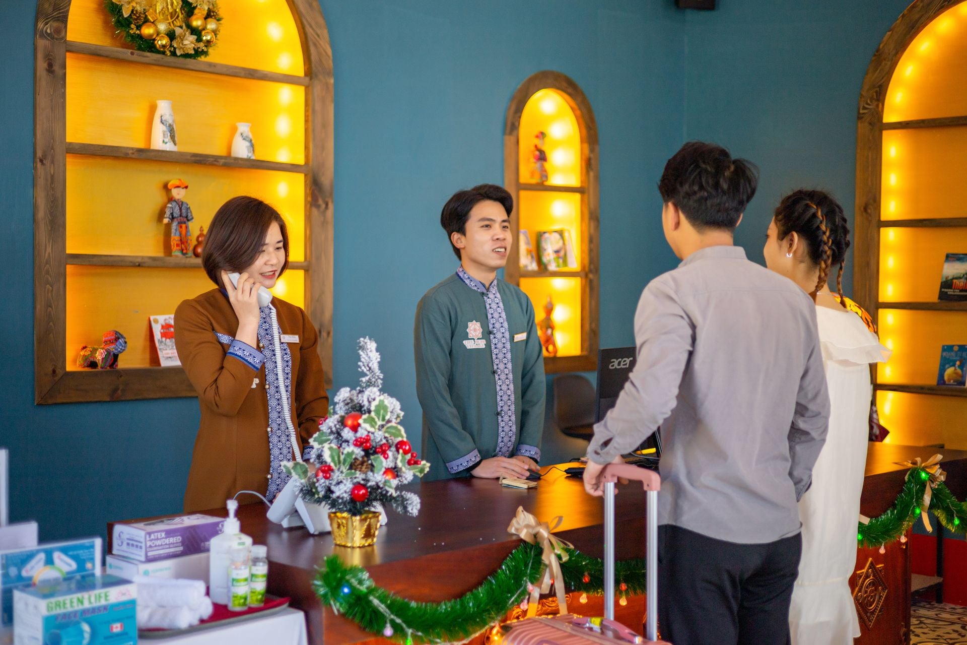 A reception desk with a Christmas tree, a small plant, and a few decorative items.