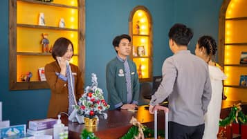 A reception desk with a Christmas tree, a small plant, and a few decorative items.