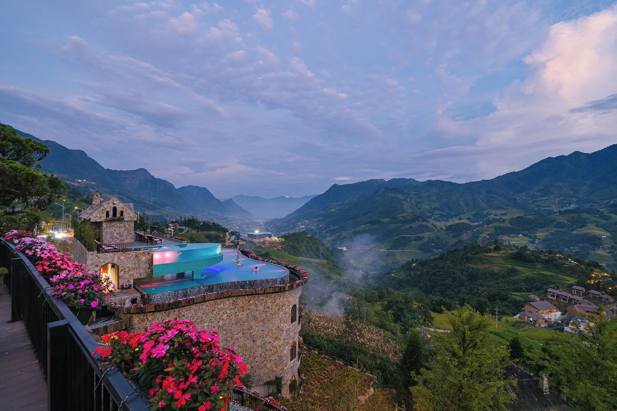 A stone building with a swimming pool and a view of a valley.