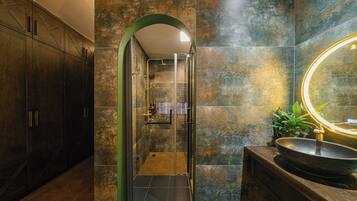 A modern bathroom with a glass-enclosed shower, a large mirror, and a wooden vanity.