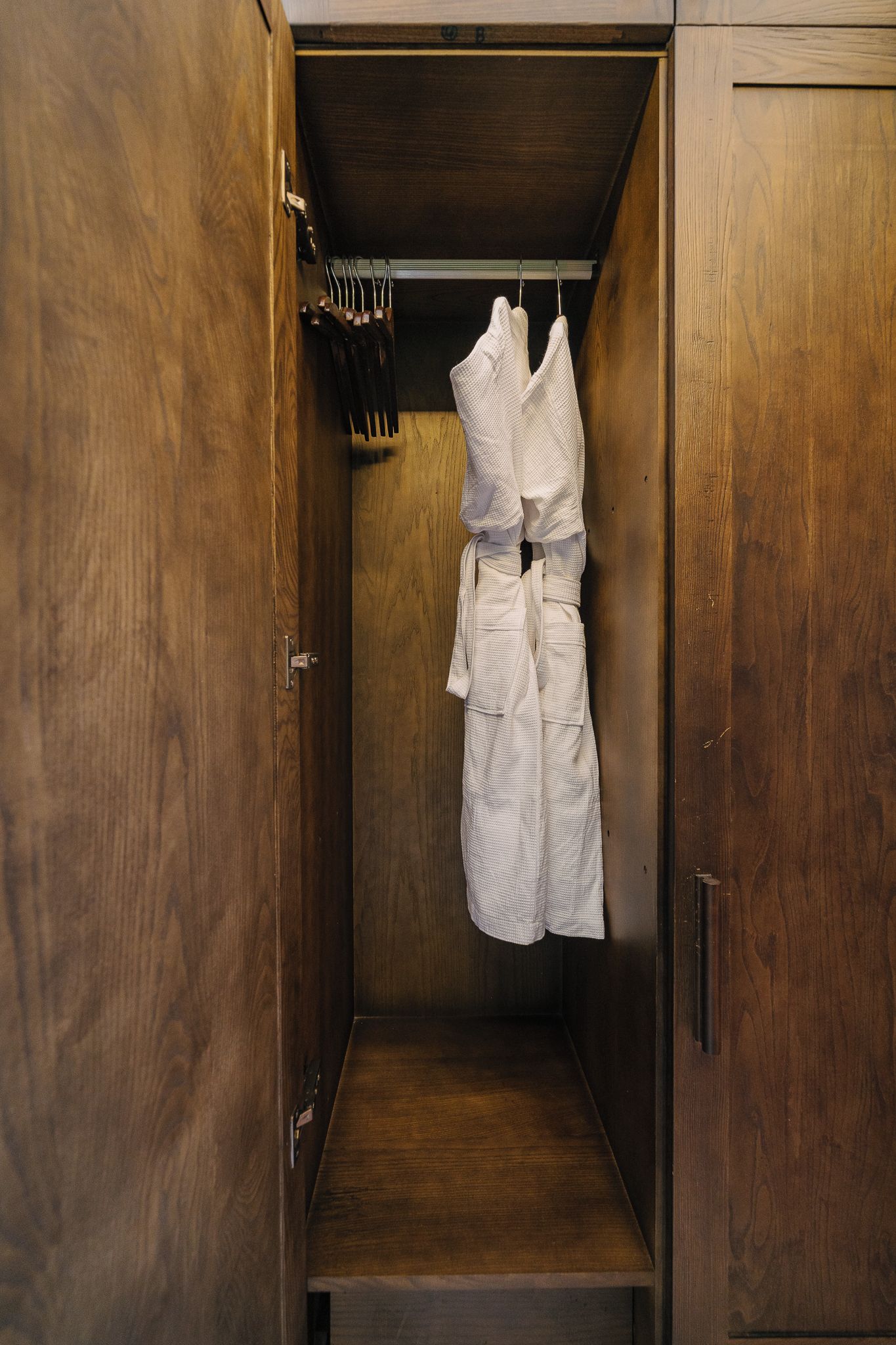 Een houten garderobe met een kledingroede en een set messen op de deur.
