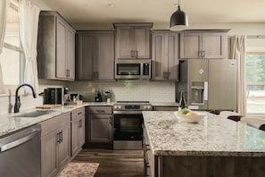 Une cuisine moderne avec des meubles en bois foncé, des appareils électroménagers en acier inoxydable et un plan de travail en granit.