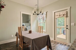 A dining area with a table set for four, a chandelier, and a view of a laundry room through an open door.