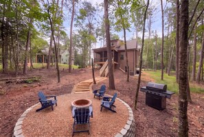 Un jardin avec un foyer, des sièges d’extérieur et un barbecue.