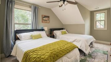 A bedroom with two beds, a ceiling fan, and large windows.