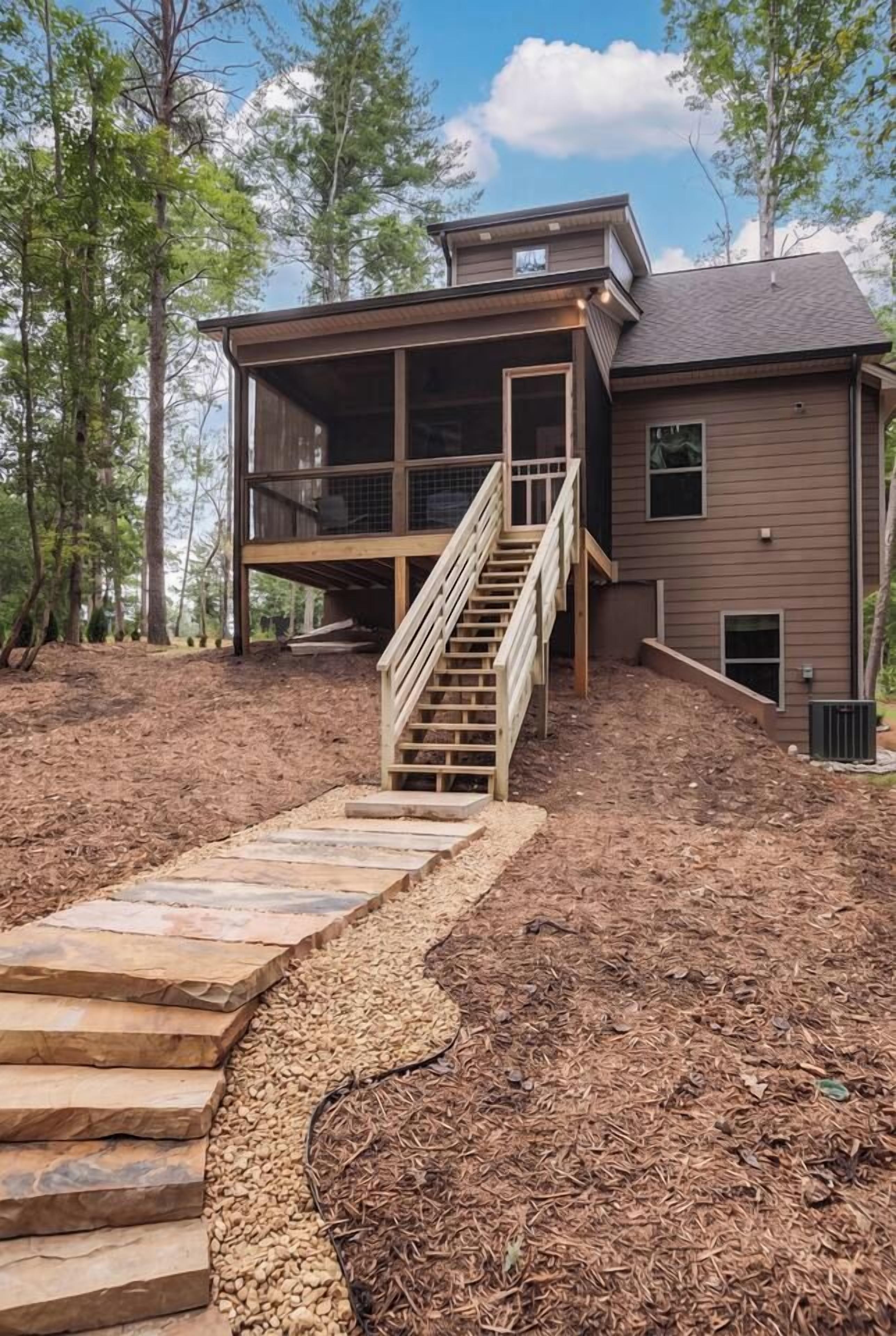 A two-story house with a wooden staircase leading to a deck.