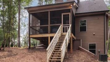 A two-story house with a wooden staircase leading to a deck.