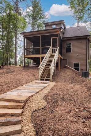 A two-story house with a wooden staircase leading to a deck.