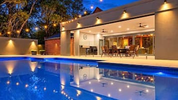 A modern outdoor pool area with a dining setup and a covered seating area.