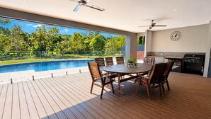 An outdoor patio with a pool, dining table, chairs, ceiling fans, and a barbecue grill. - Blumberg Mews - Stunning Adelaide Hills Retreat Near Barossa (Birdwood)