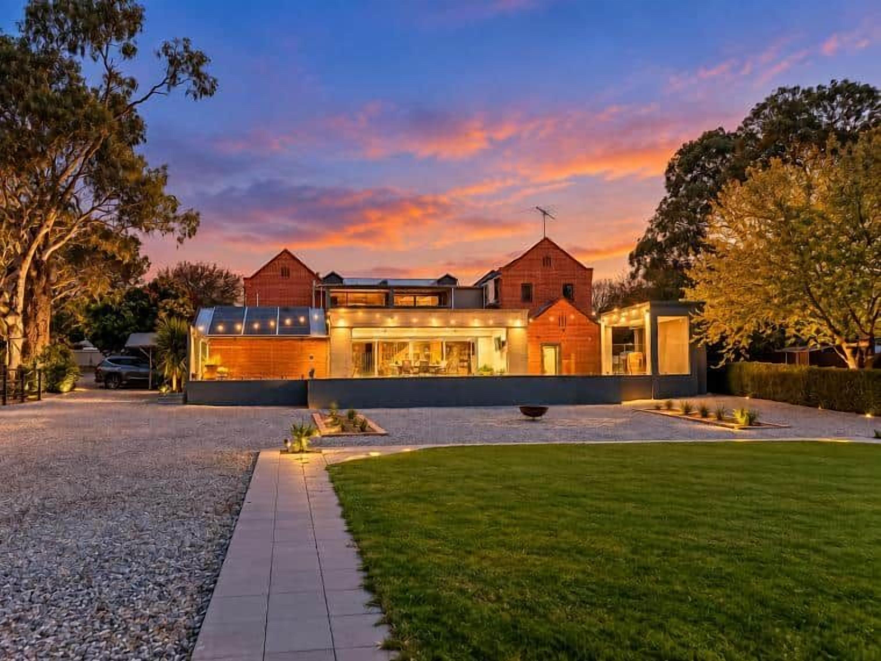 Una casa moderna con un amplio camino de entrada, un césped cuidado y un gran ventanal con vistas a la propiedad.