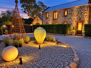 A stone building with a gravel driveway and a decorative metal sculpture.