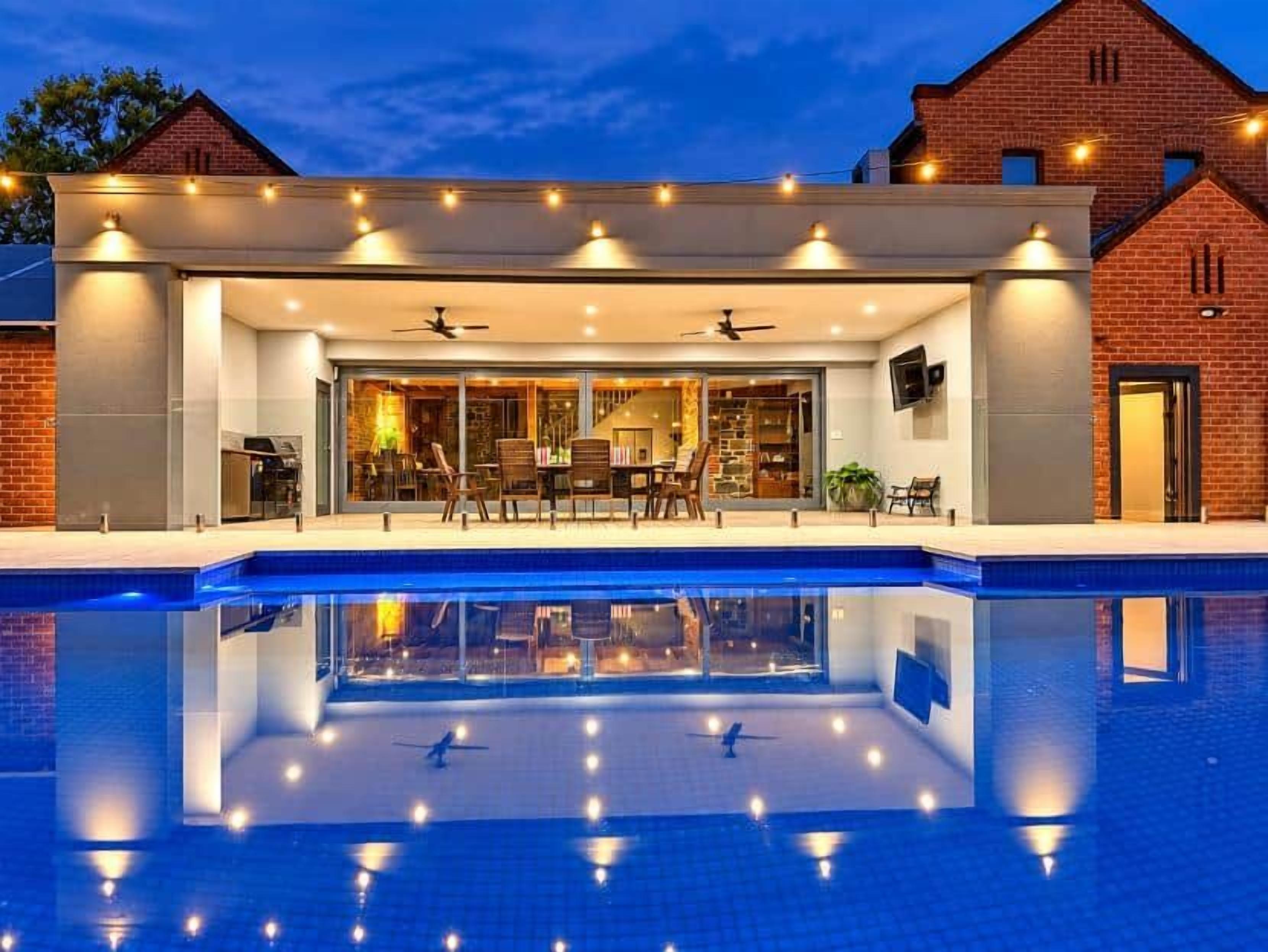 A modern house with a swimming pool, a covered patio, and a brick exterior.