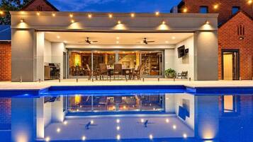 A modern house with a swimming pool, a covered patio, and a brick exterior.
