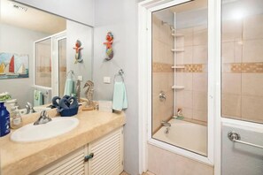 Une salle de bain équipée d’un lavabo, d’un miroir et d’une douche à parois de verre.