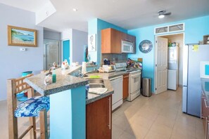 A modern kitchen with a central island, built-in appliances, and a view into the dining area.