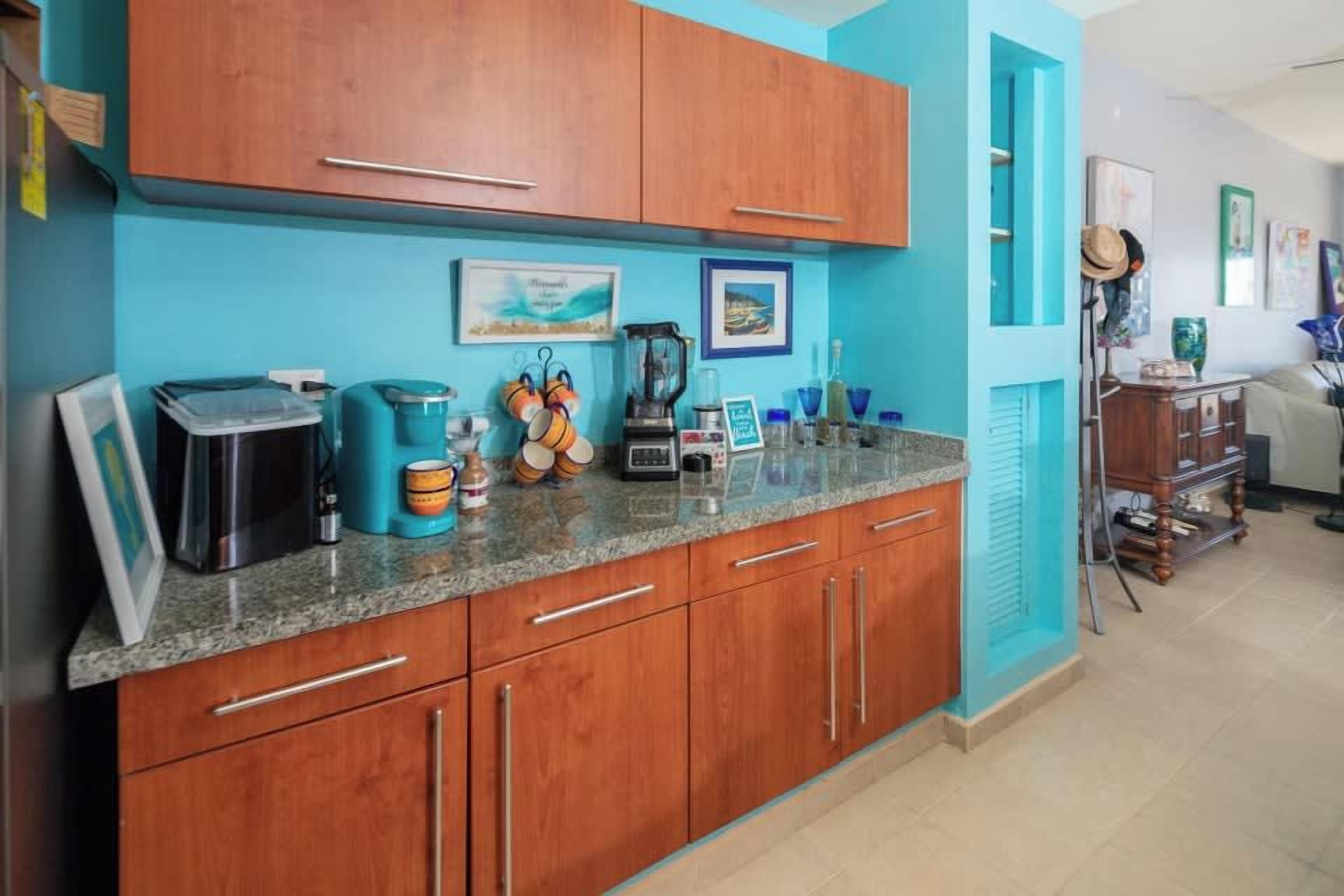 A kitchen with wooden cabinets, a granite countertop, and various kitchen appliances.