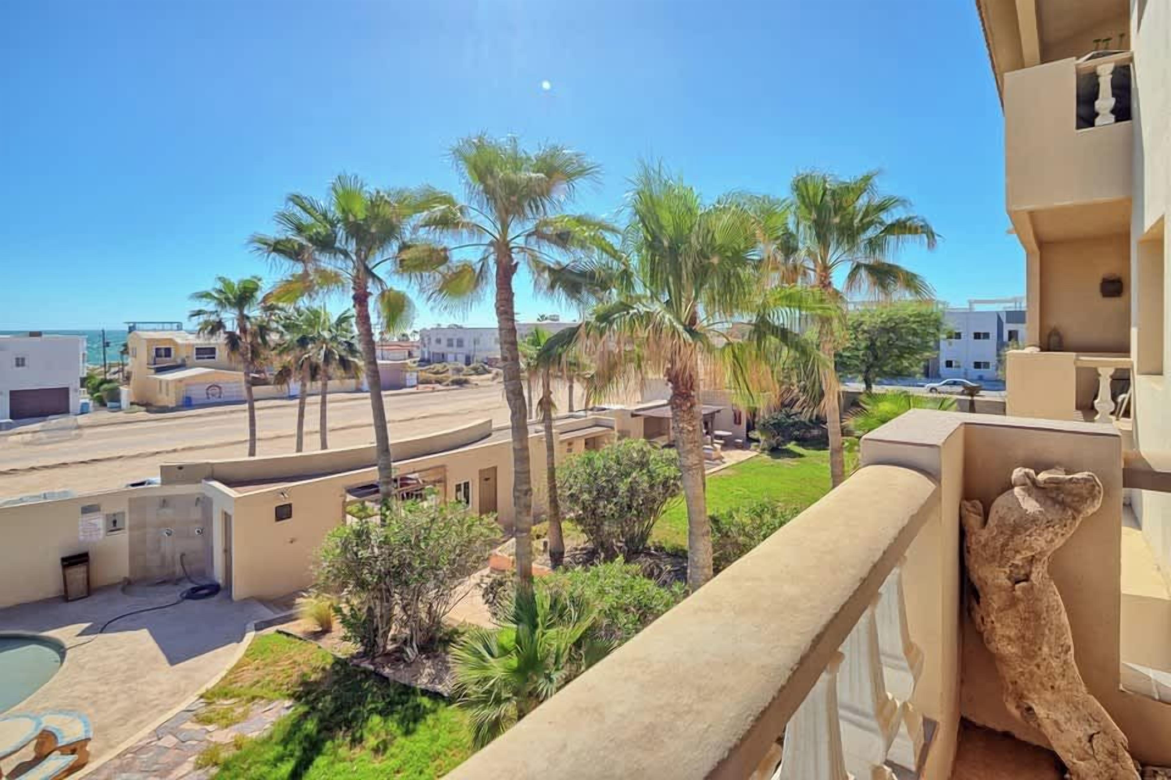 Een hotelbalkon met uitzicht op palmbomen en een zwembad.