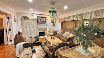 A traditional living room with a fireplace, a dining table, and a sofa set.