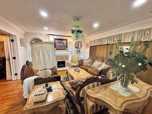 A traditional living room with a fireplace, a dining table, and a sofa set. - Elegant 1925 Vintage Home (Detroit)