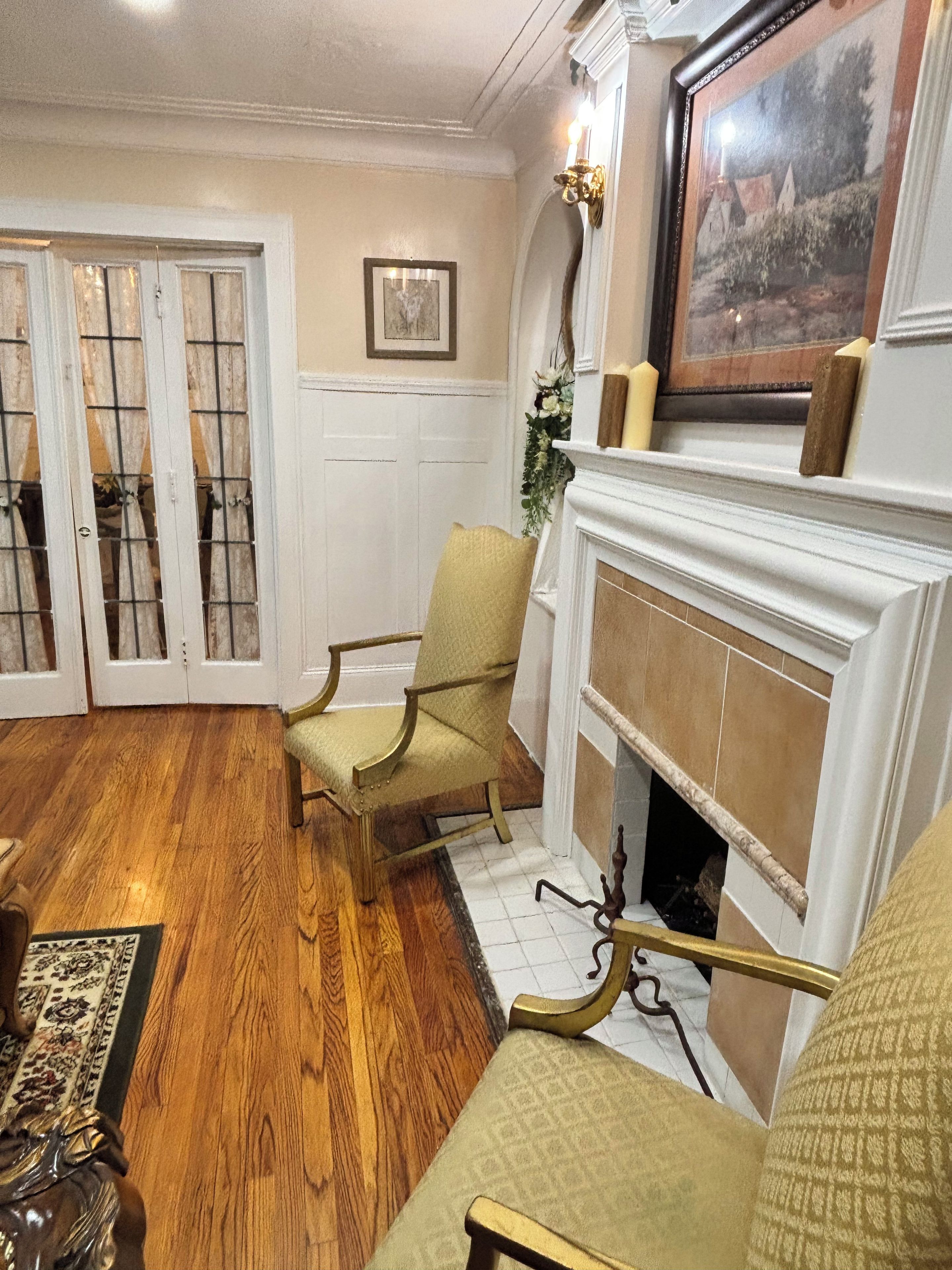 A room with a fireplace, two chairs, a rug, and a door with glass panels.