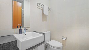 Casa de banho moderna com lavatório branco, sanita e zona de duche.