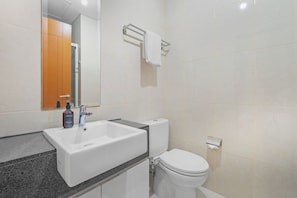 Un baño moderno con lavamanos blanco, inodoro y zona de ducha.