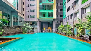 Piscina com superfície de água azul cristalina, rodeada por edifícios modernos com varandas e janelas amplas.