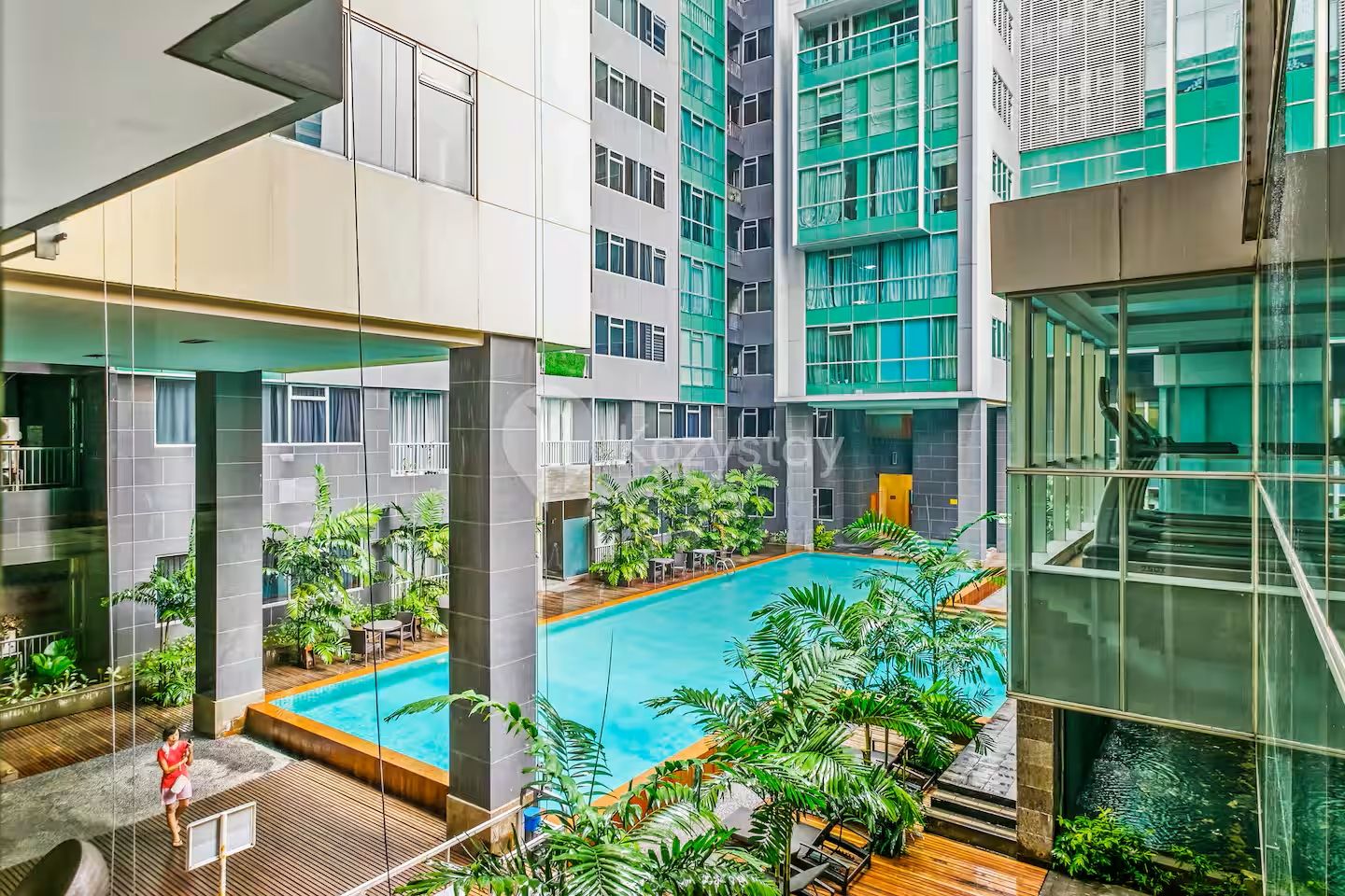 A modern building with a central swimming pool surrounded by greenery.