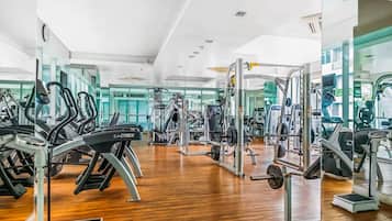 Un gimnasio con máquinas de cardio, equipo de levantamiento de pesas y espejos en las paredes.