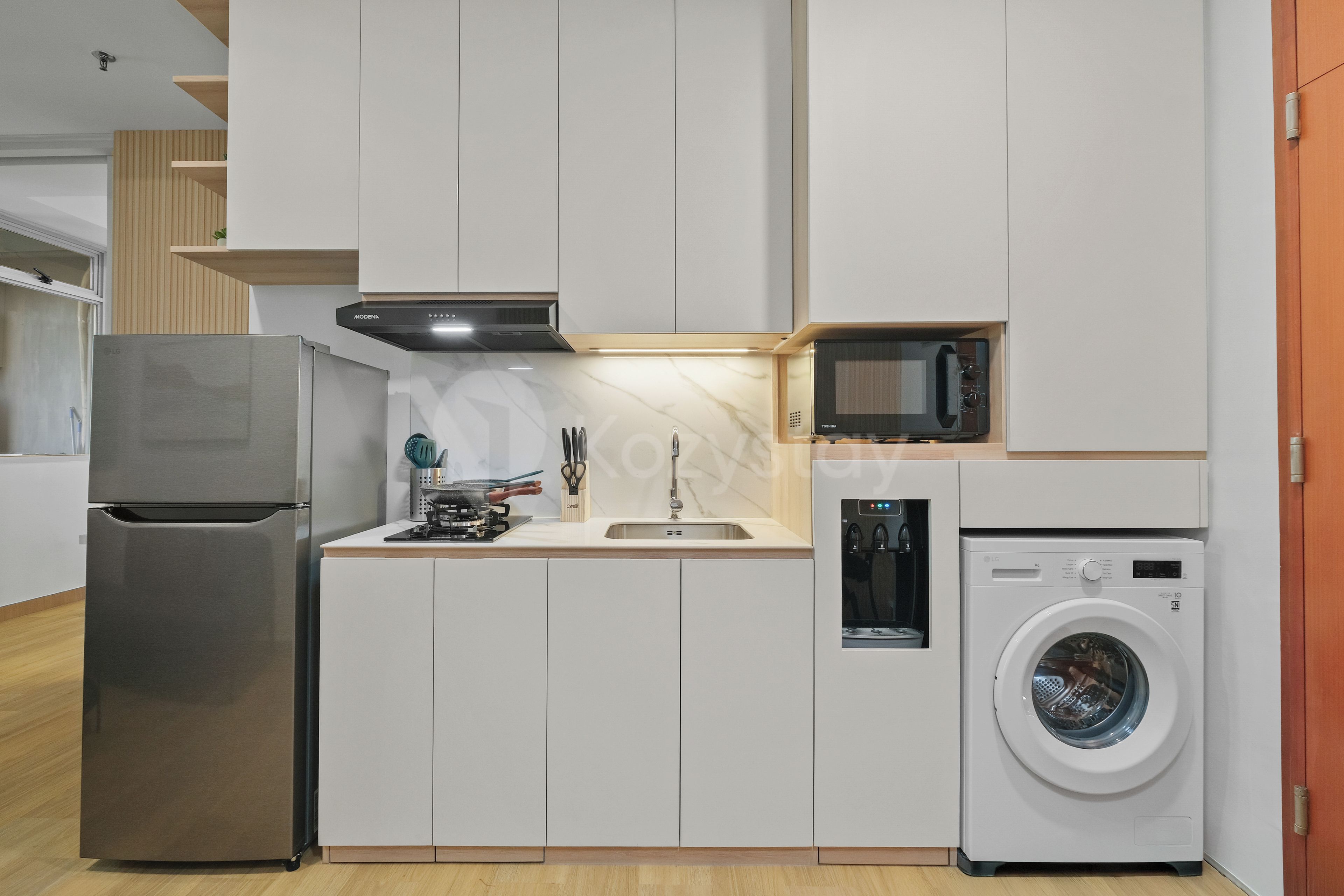Een praktische keuken met een koelkast, magnetron en wasmachine.