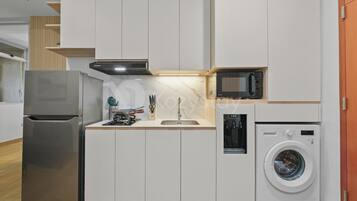 Een praktische keuken met een koelkast, magnetron en wasmachine.