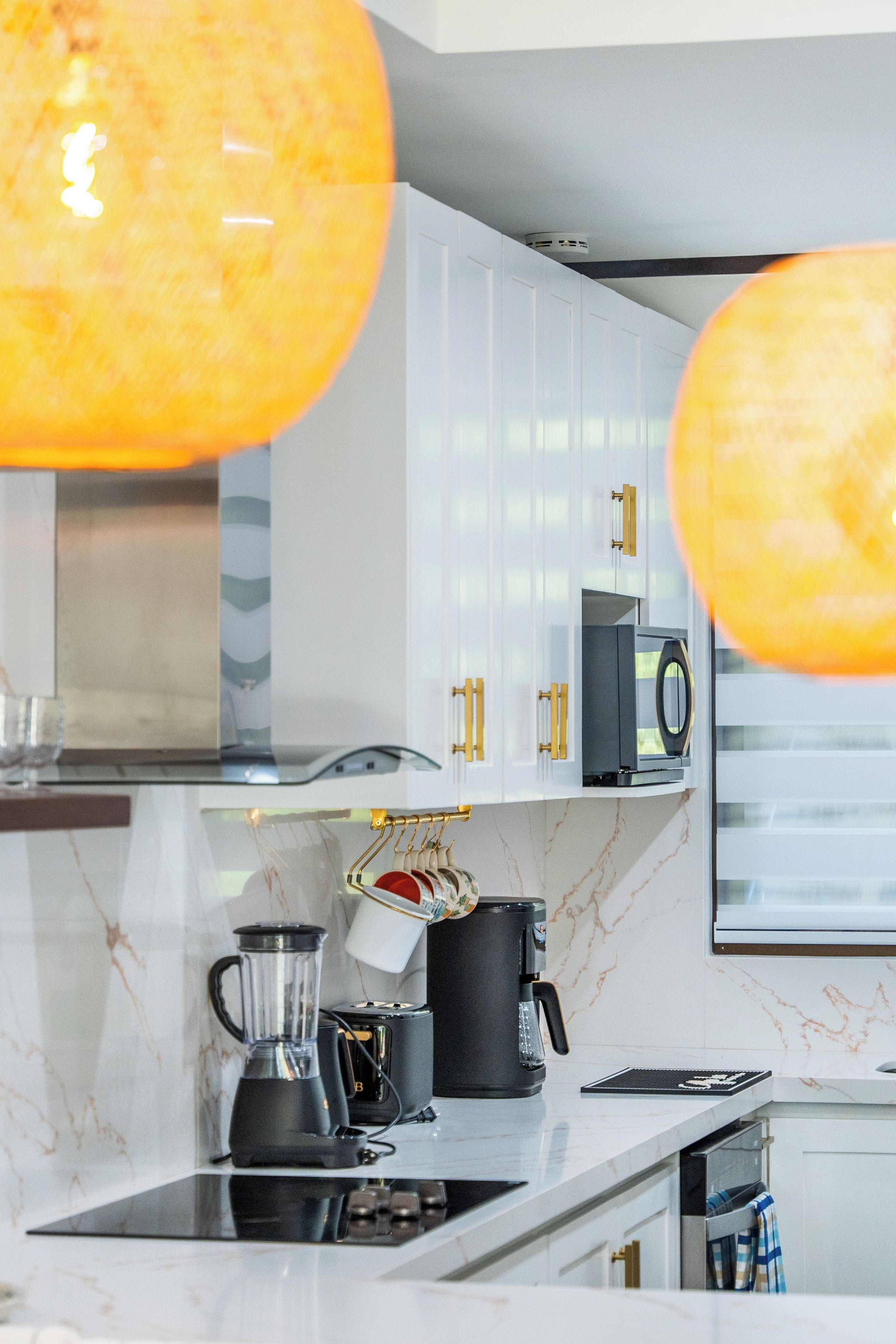 A modern kitchen with white cabinets, a black coffee maker, and a blender on the counter.