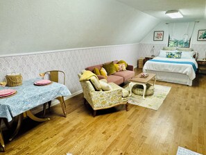 A cozy room with a dining table set for two, a sofa, a chair, and a bed.