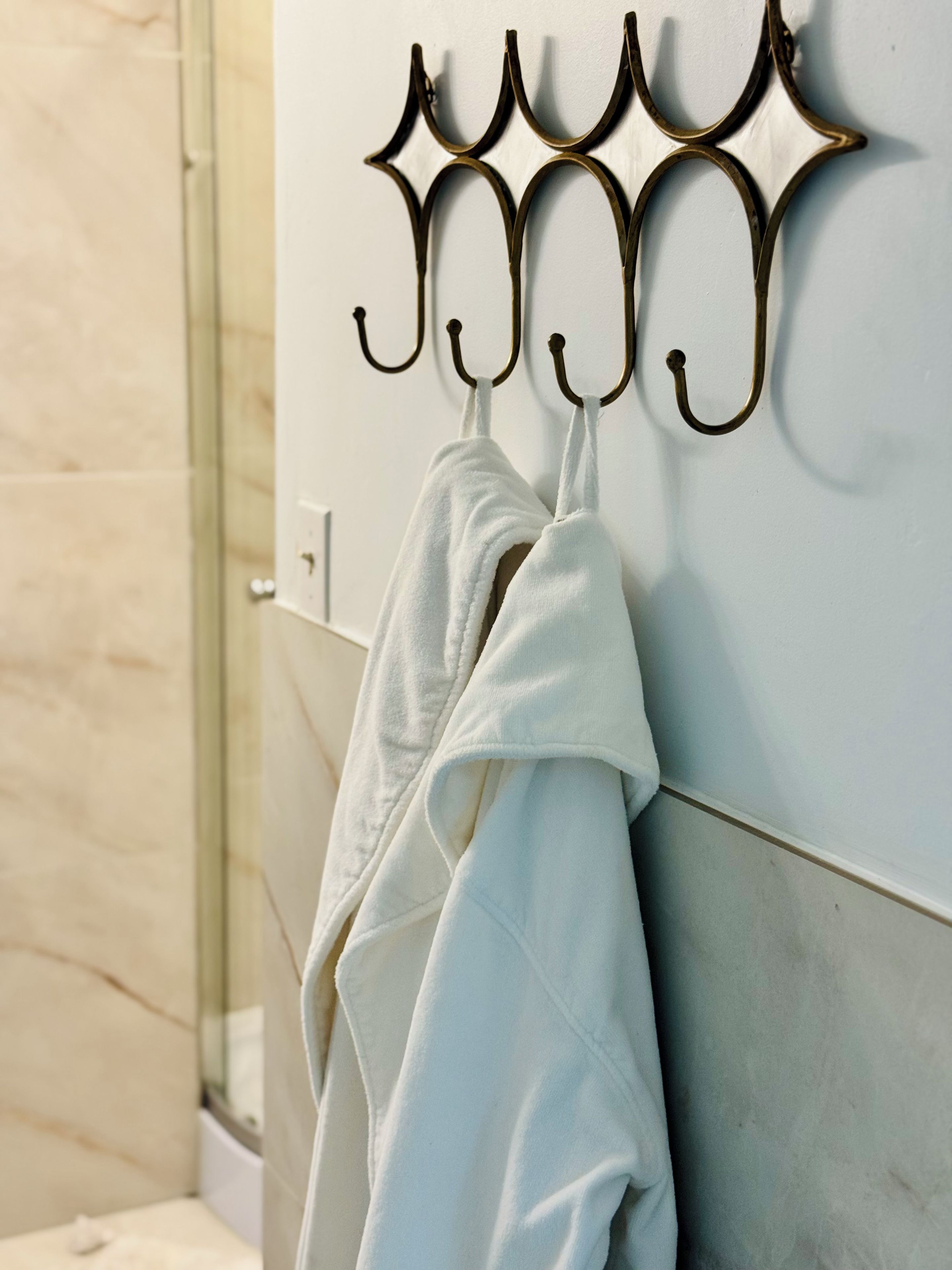 Een badkamer met een handdoekhouder met twee handdoeken, een douche en een wand betegeld met marmer.