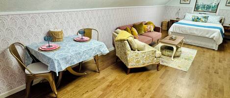 A cozy room with a dining table set, a sofa, a bed, and a window with curtains.