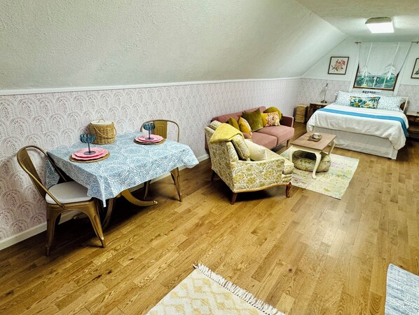 A cozy room with a dining table set, a sofa, a bed, and a window with curtains.