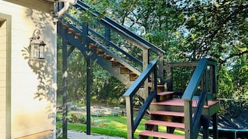 A wooden staircase leading to a building with a lantern on the wall.