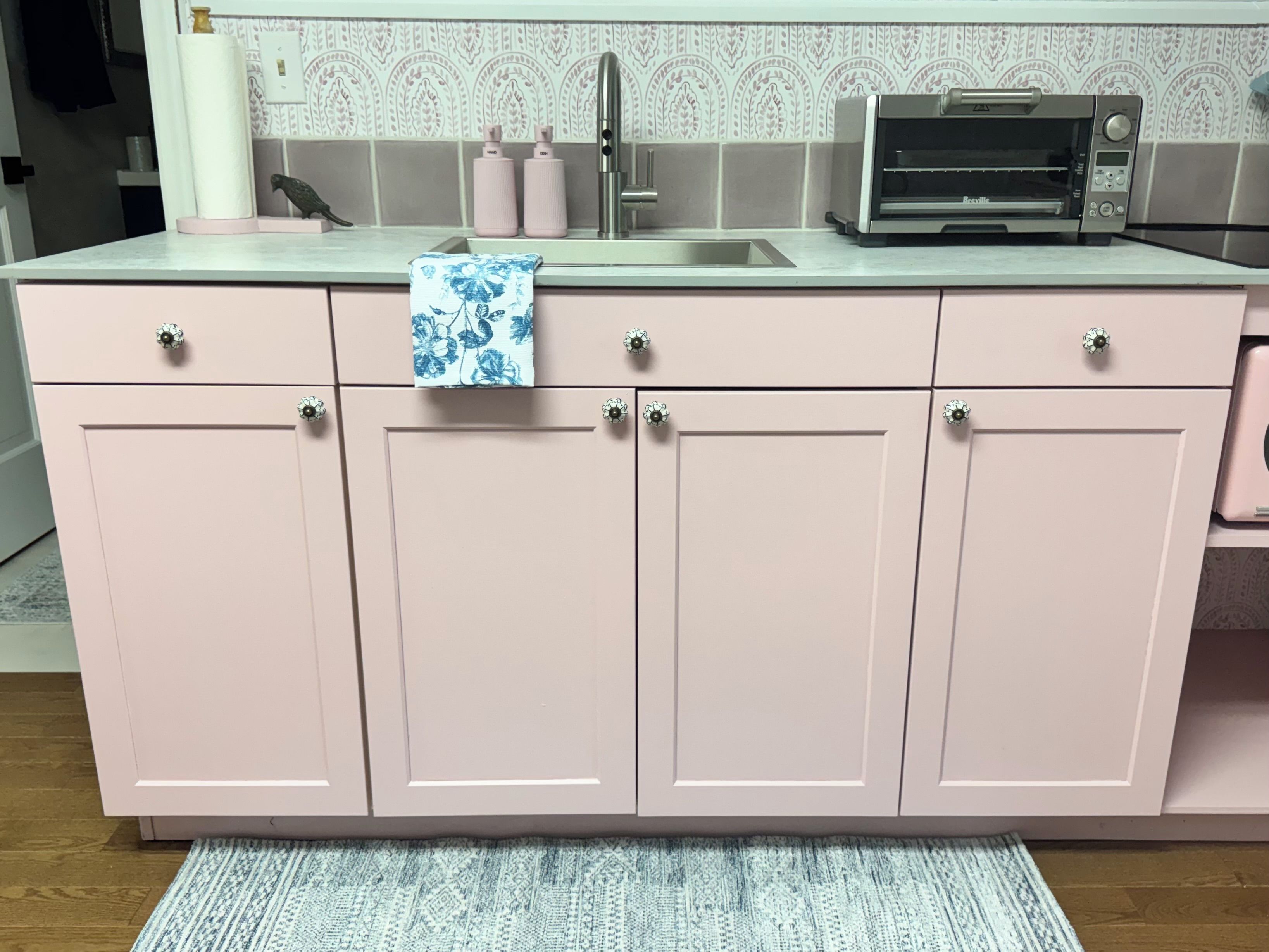 A kitchen with a countertop, a sink, a toaster, and cabinets.