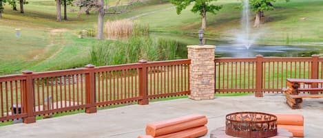 A patio area with a fire pit, seating, and a view of a golf course.